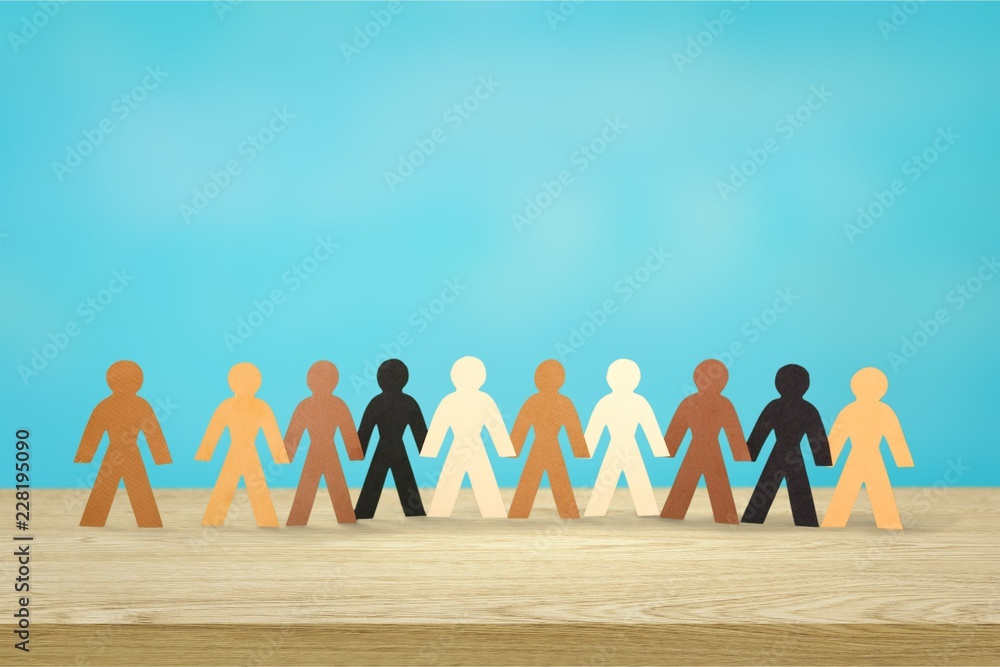 Row of paper people holding hands on table on light background