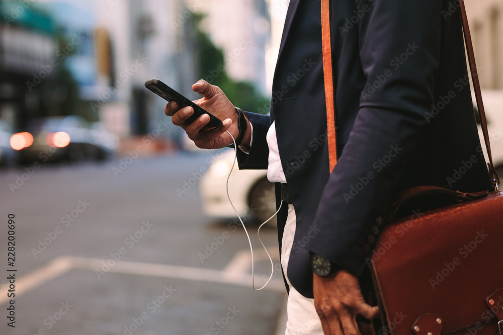 Businessman walking outdoors using mobile phone