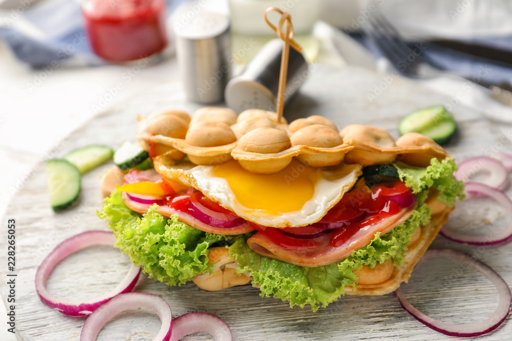 Delicious bubble waffle with fried egg on wooden board