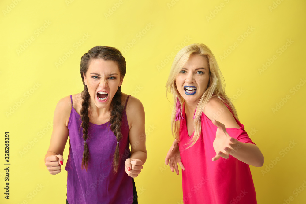 Portrait of beautiful aggressive women on color background