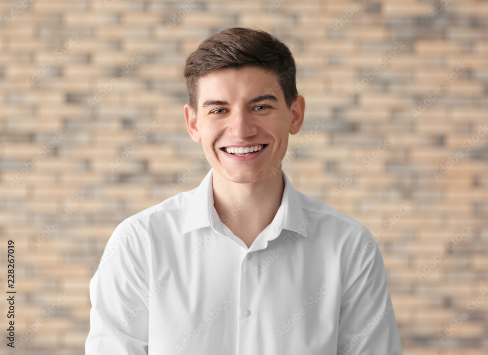 Portrait of handsome smiling young man against brick wall