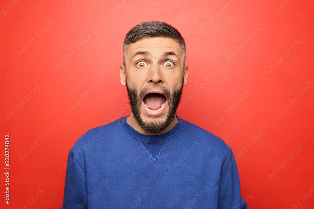 Portrait of shocked man on color background