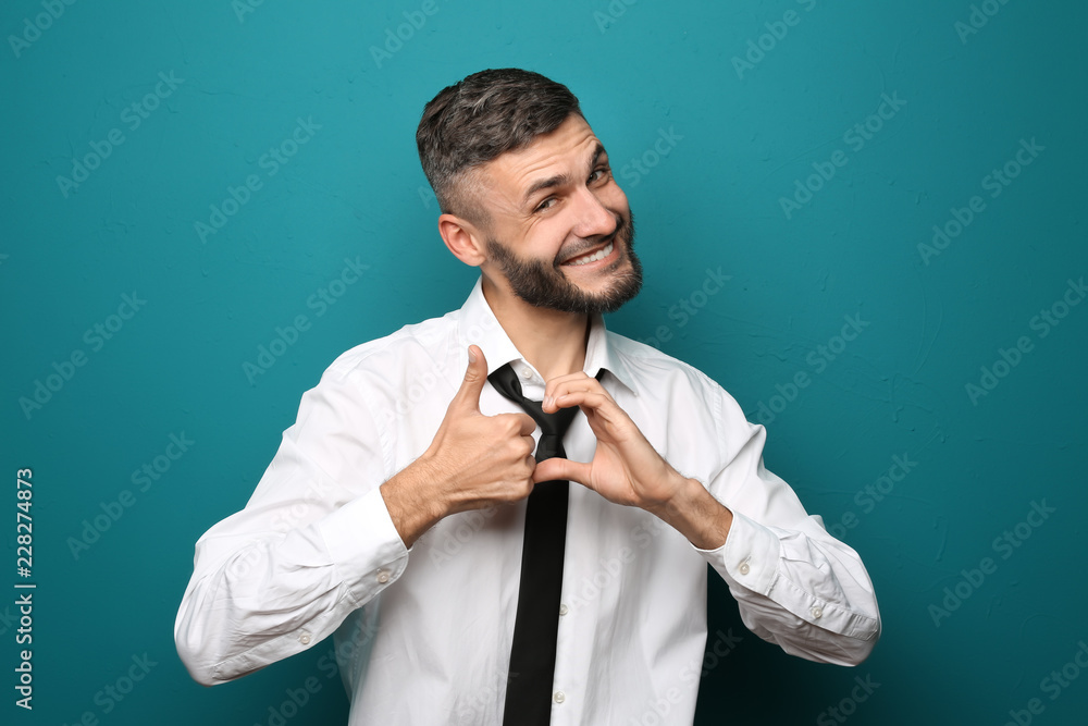 Happy businessman showing thumb-up gesture on color background