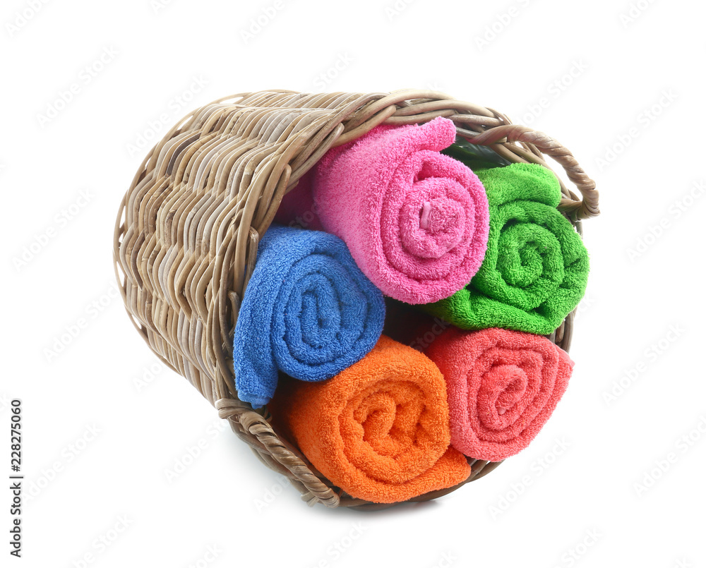 Wicker basket with rolled bright towels on white background