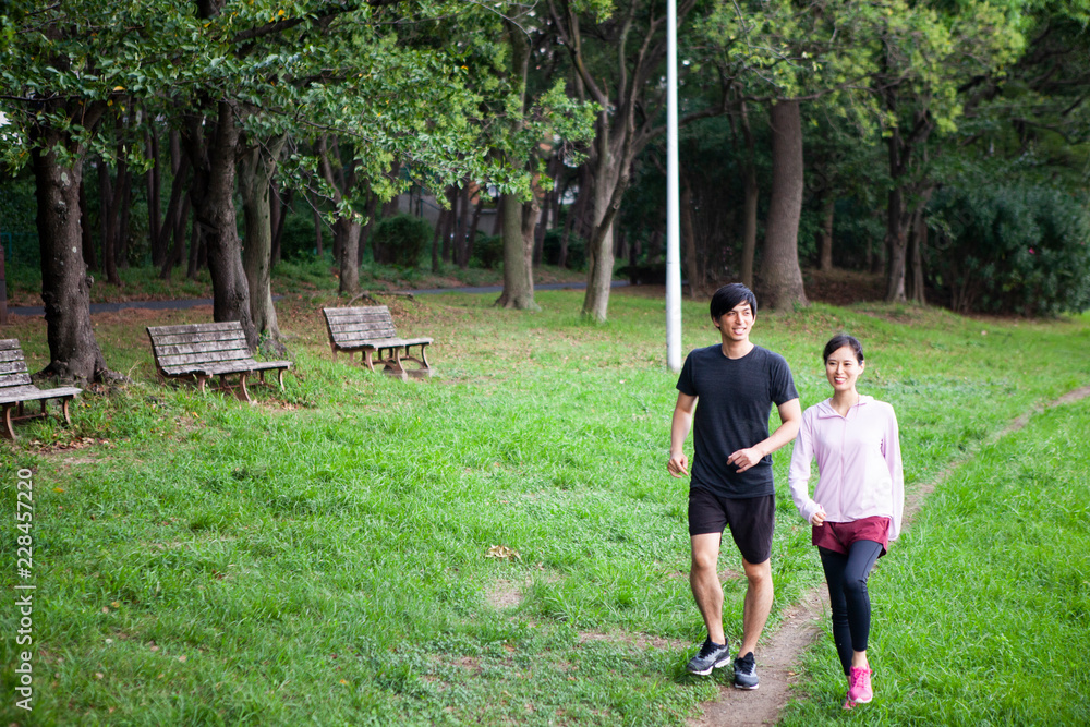 公園をウォーキングする夫婦。