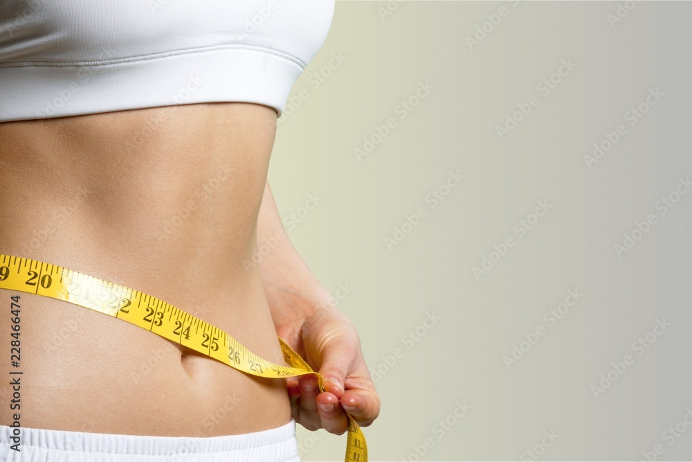 Slim young woman measuring her thin waist