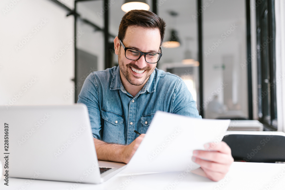 Handsome young smiling businessman working with documents.