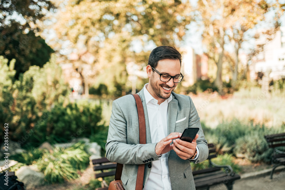 Happy elegant man using smartphone outdoors.