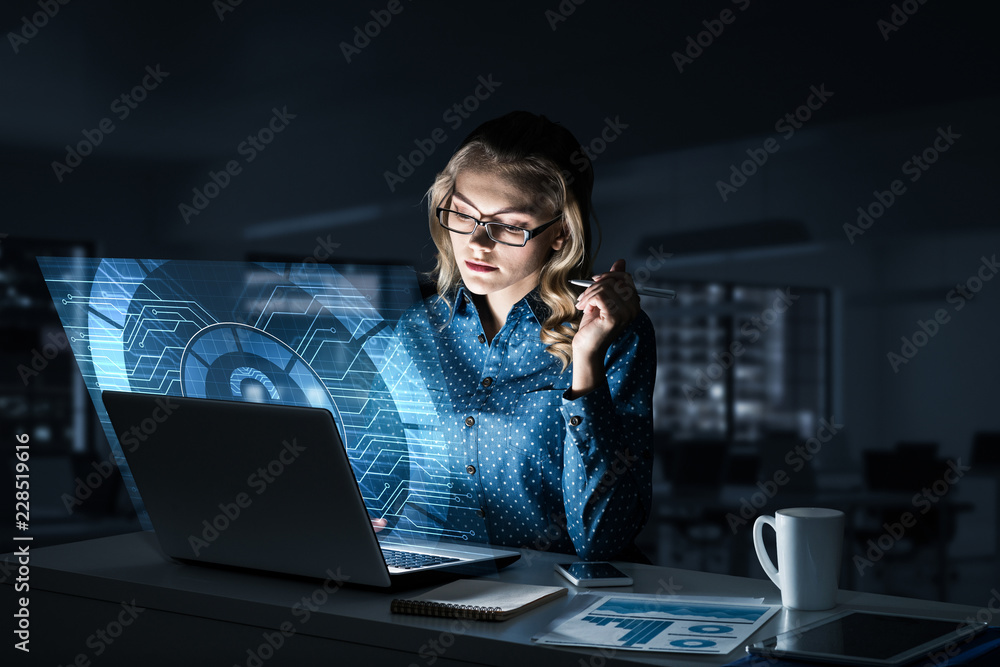 Beautiful blonde in dark office working on laptop and getting ne