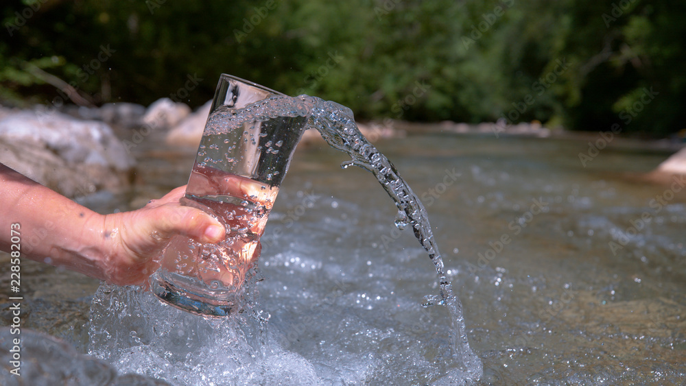 CLOSE UP: Unknown person gathers the crystal clear water from a calm spring.