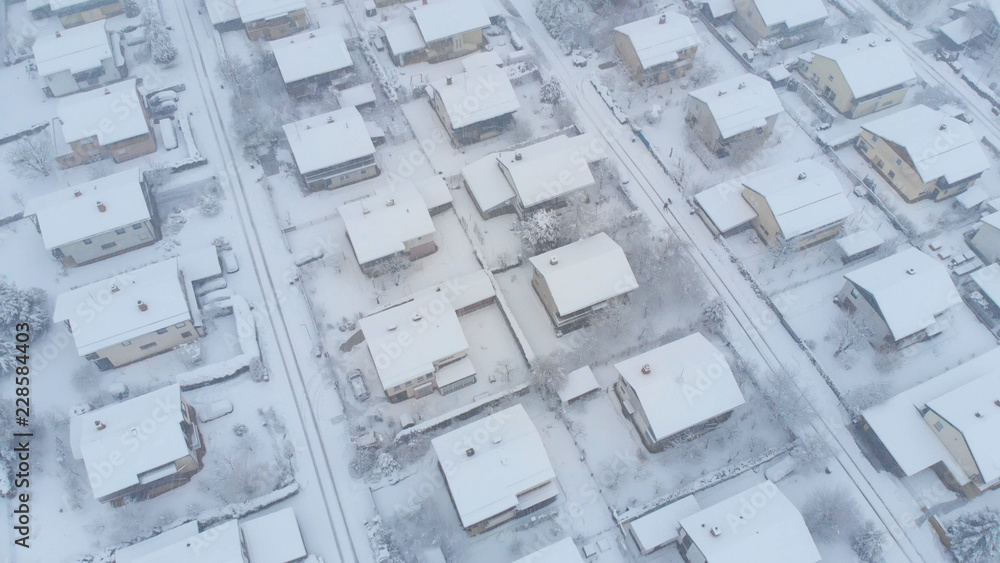 AERIAL: Flying above the snowy rooftops and streets of suburban neighborhood.