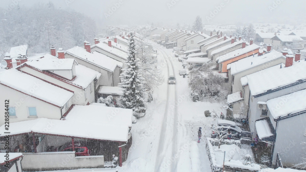 AERIAL：汽车行驶在通往郊区社区的雪道上