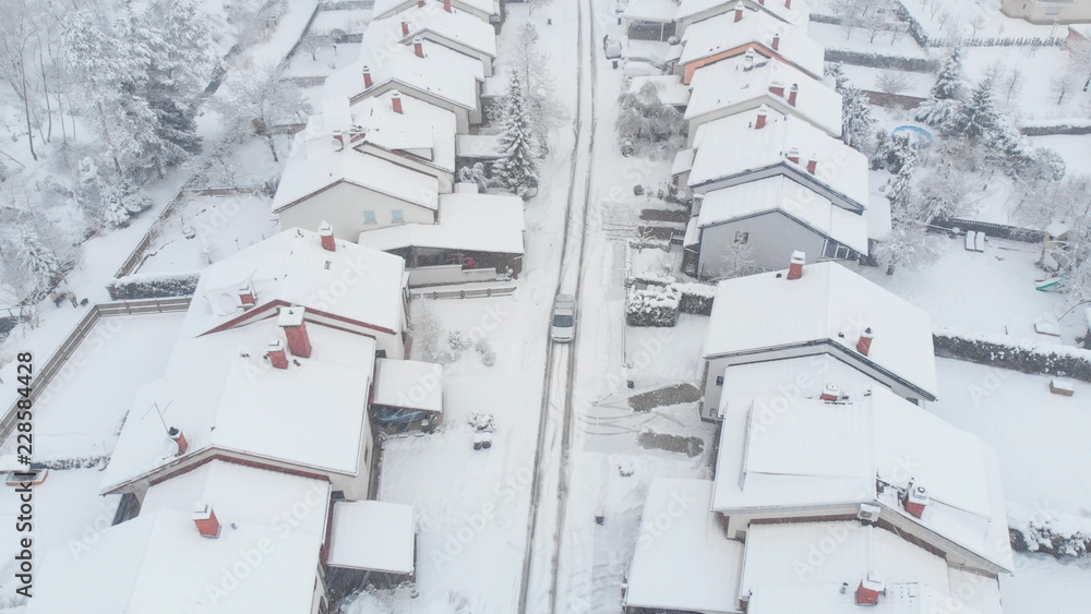 AERIAL：银色汽车在通往郊区的雪道上行驶。