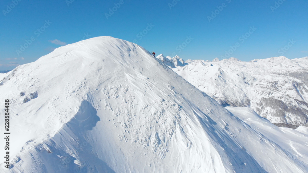 空中飞雪：在阳光明媚的冬天，不知名的滑雪者在雪山上徒步旅行。