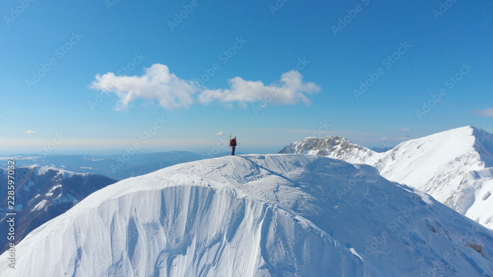 空中：无名滑雪者徒步登上阿尔卑斯山的雪山山顶。