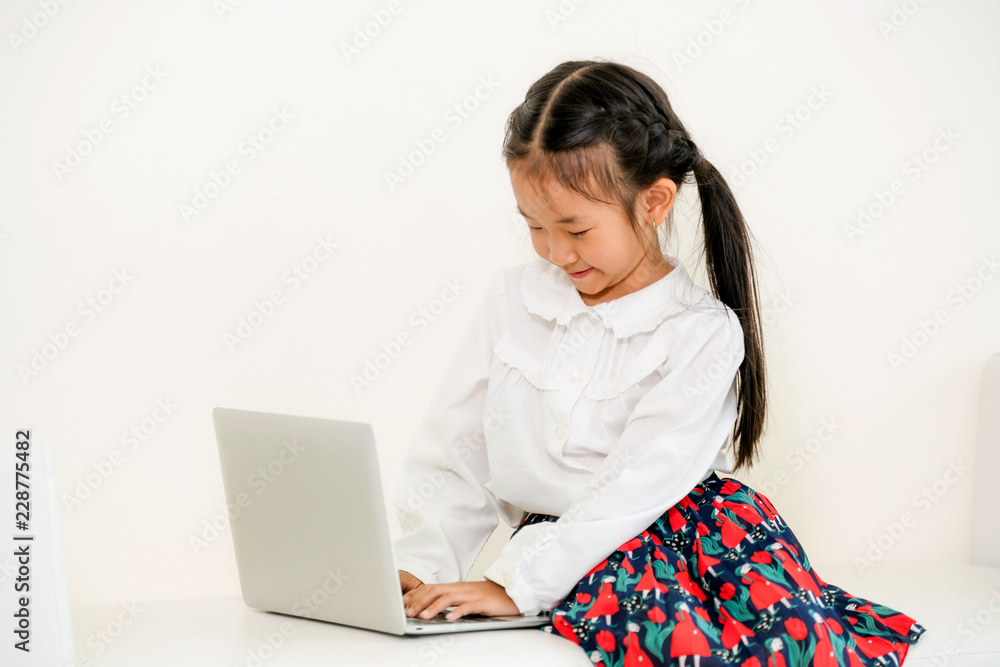 Little kid using laptop computer on white sofa.