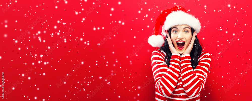 Happy young woman with Santa hat on a red background