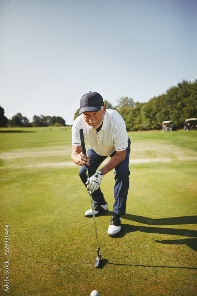 Senior golfer checking a golf green before putting