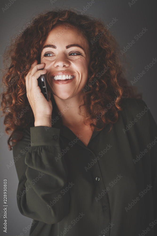 Young businesswoman talking on her cellphone against a gray back