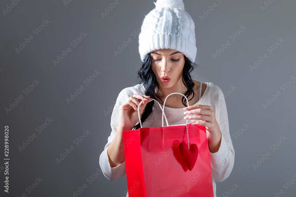 Happy young woman holding a shopping bag on a gray background