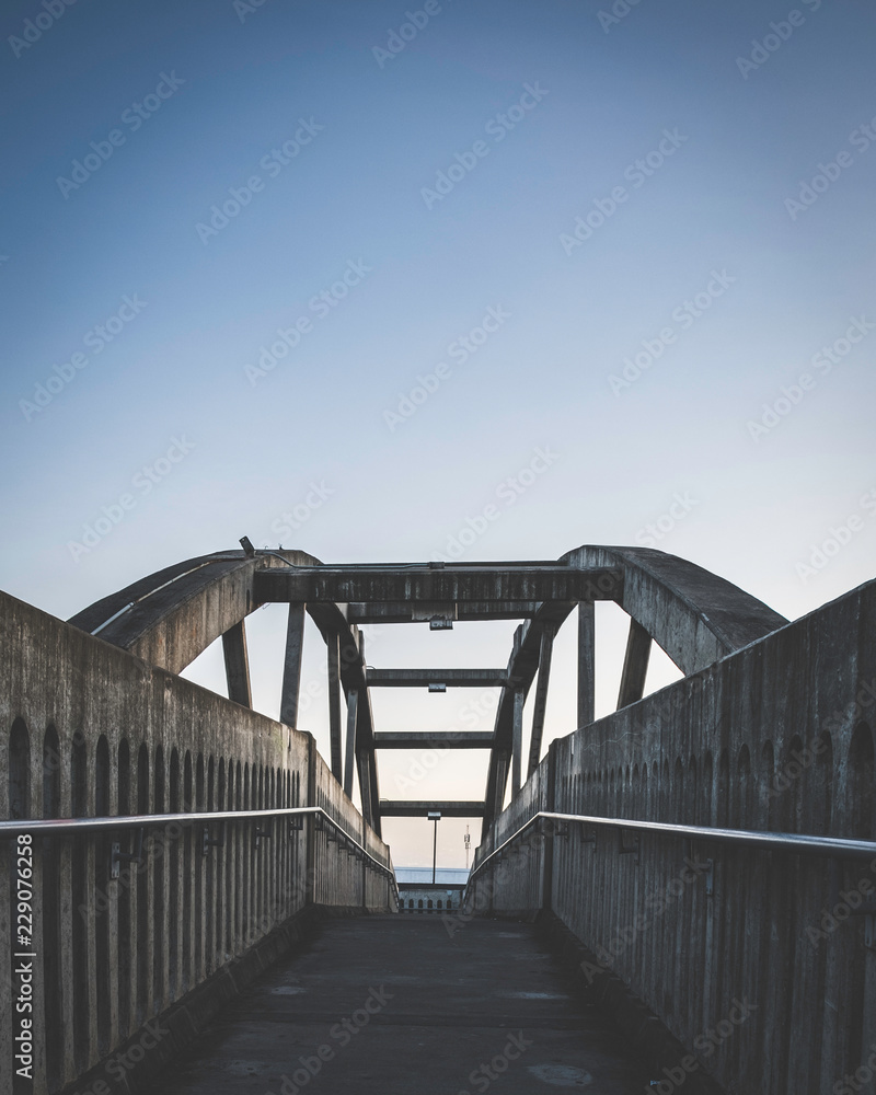 low perspective view along a concrete pedestrian bridge at sunrise