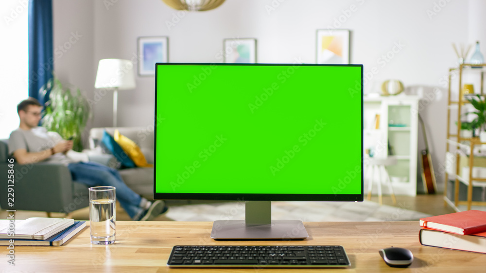 Modern Personal Computer with Green Mock-up Screen Display Standing on the Desk in the Cozy Living R