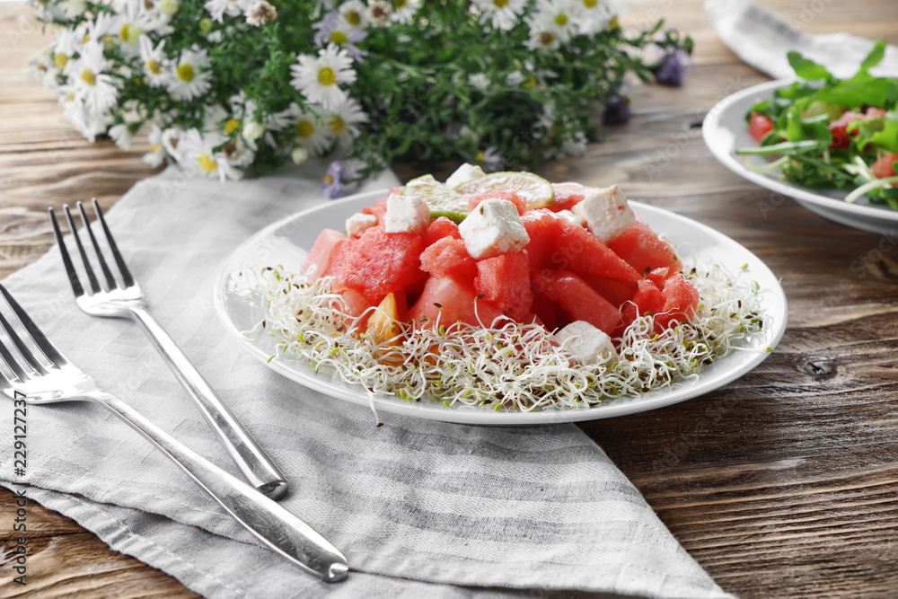 Plate with delicious watermelon salad on wooden table