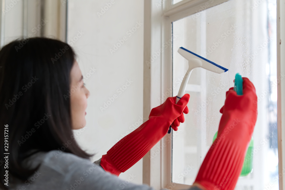 Side view of young Asian girl wearing in grey shirt and red protective gloves with glass cleaning eq