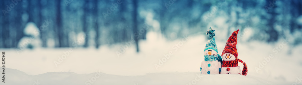 little knitted snowmans on soft snow on blue background