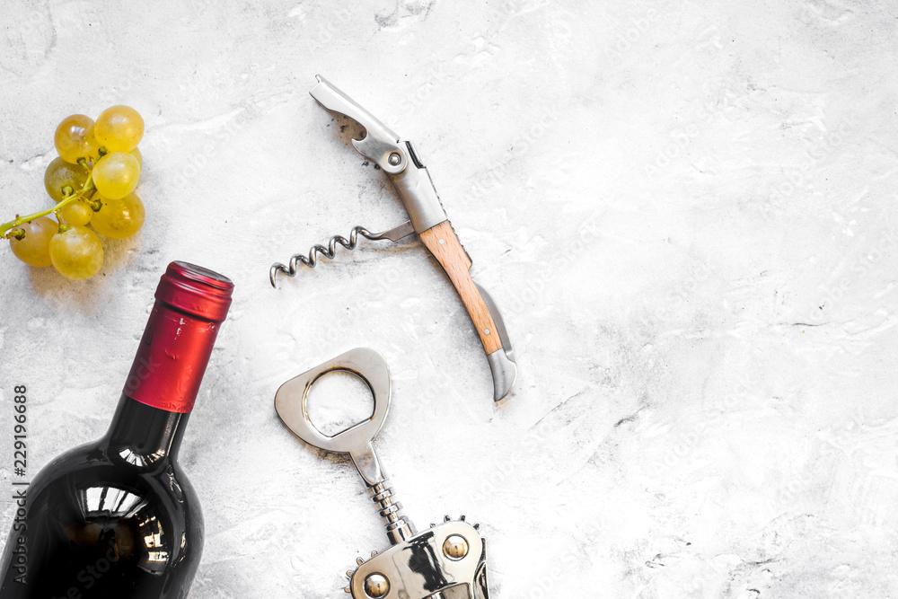 glass wine bottle and corkscrew on concrete background top view