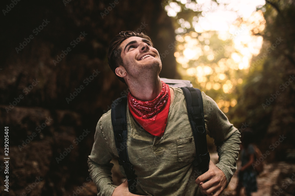 微笑的年轻人徒步登山抬头看