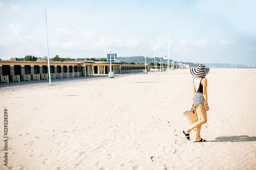 Woman walking on the beach with locker rooms in Deauville, famous french resort in Normandy. Wide an