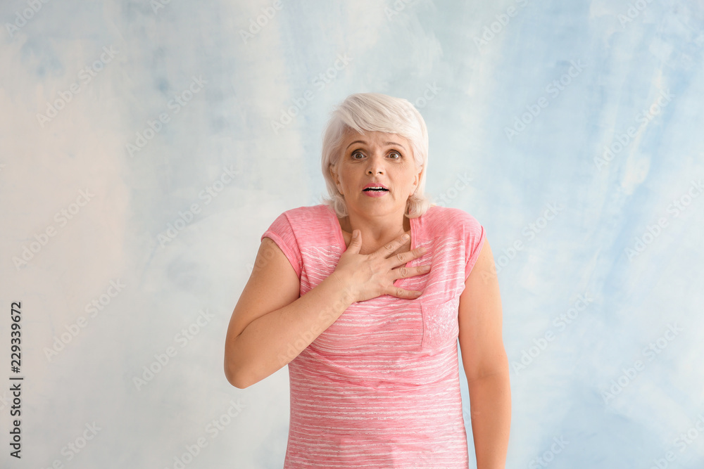 Portrait of shocked mature woman on light background