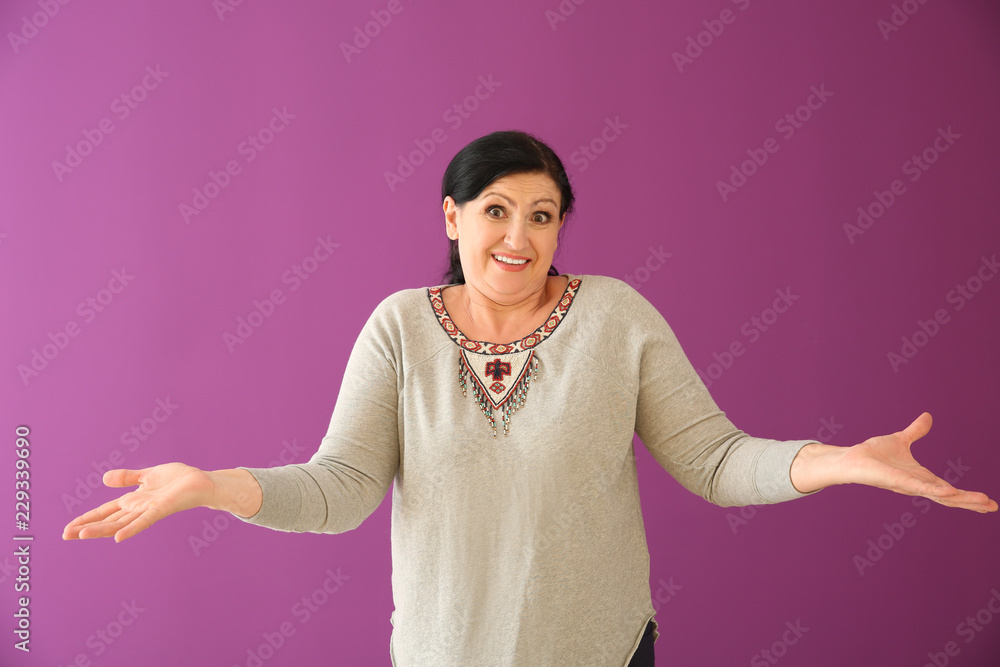 Portrait of surprised mature woman on color background