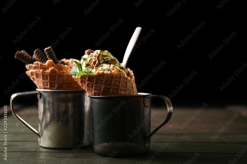 Metal cups with waffle cones and delicious ice cream on wooden table