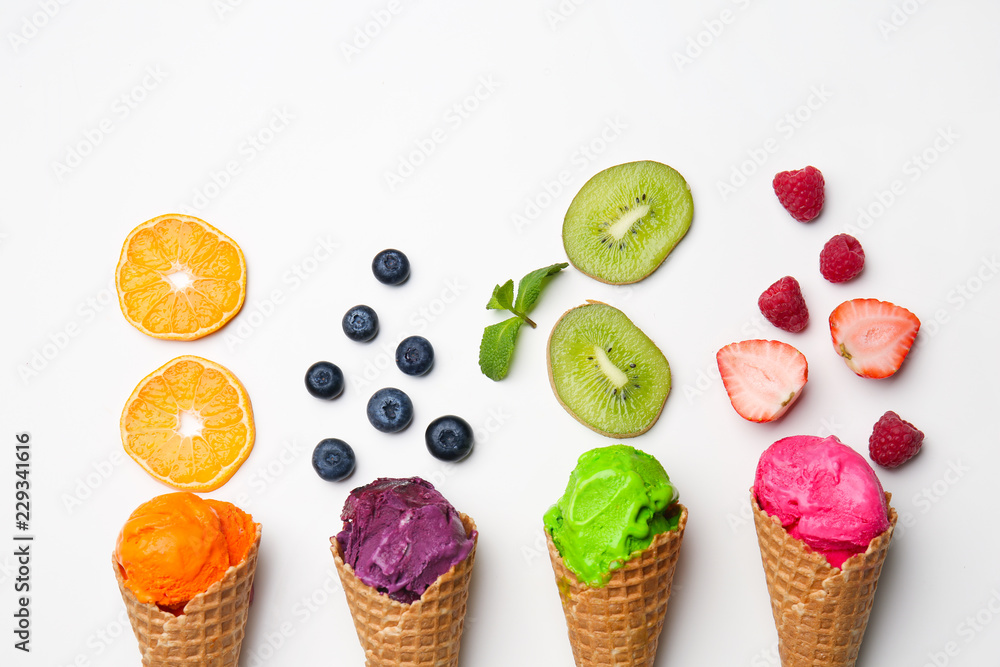 Waffle cones with delicious color ice cream, fruits and berries on white background