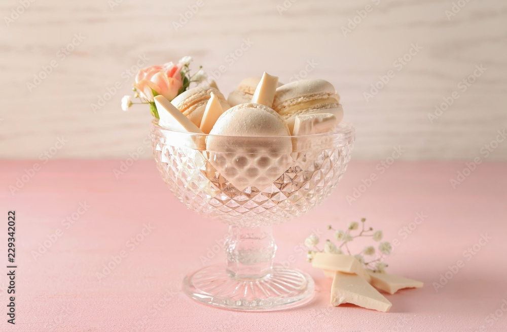 Dessert bowl with sweet macaroons and white chocolate on color table