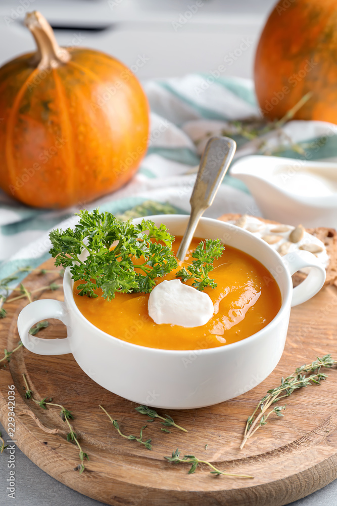 Casserole with tasty pumpkin cream soup on wooden board