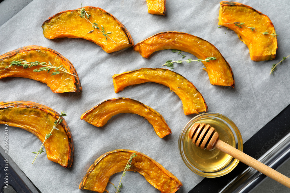 Tasty cooked pumpkin pieces with honey on baking tray