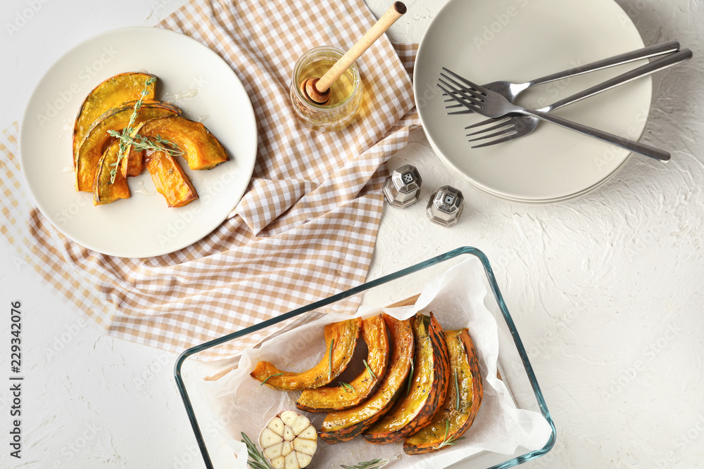 Tasty baked pumpkin pieces with honey on white table