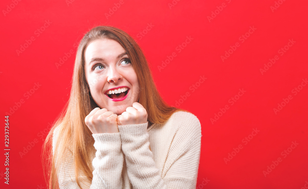 Happy hopeful wishful young woman on a solid background