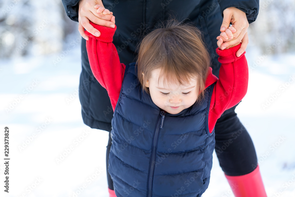 蹒跚学步的男孩和妈妈在雪地里玩耍