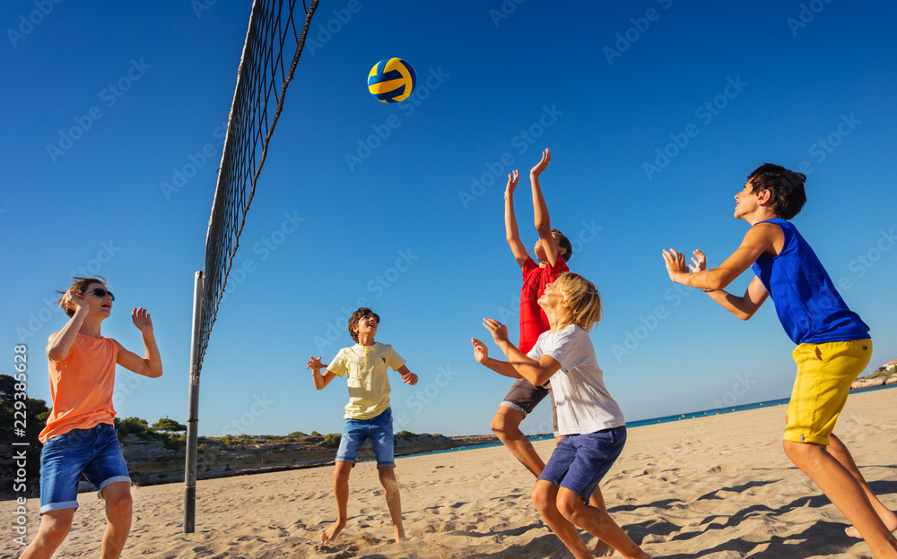 Teenage boys playing volleyball on the beach