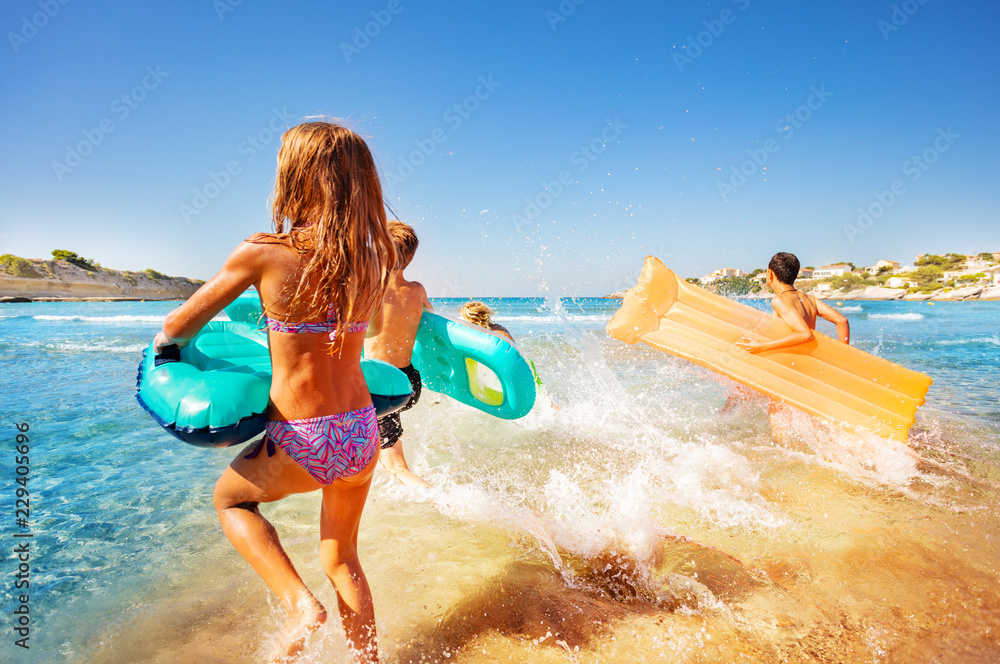 Happy kids splashing water while running into sea