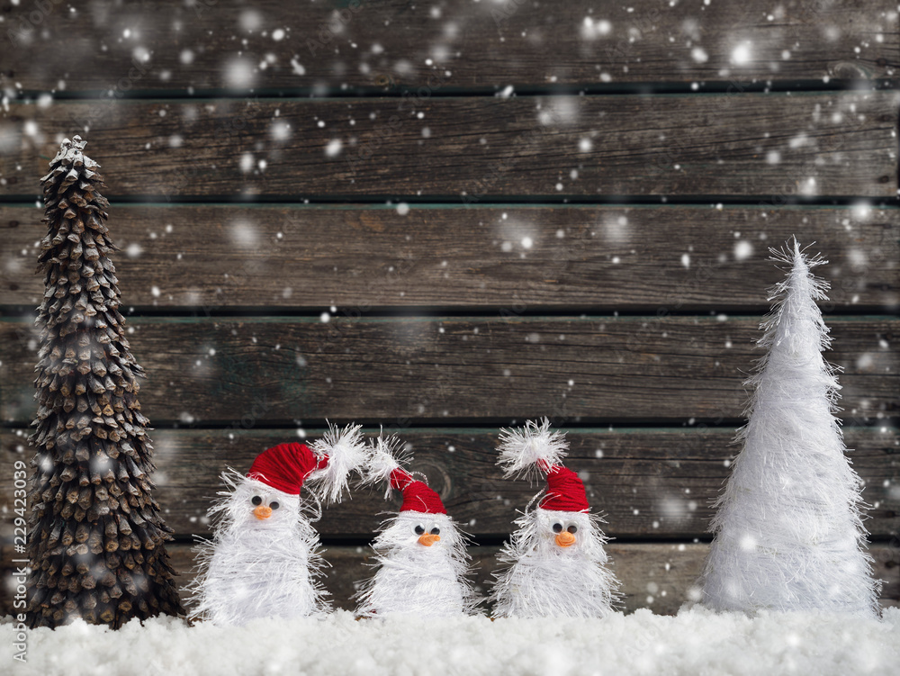 little knitted snowmans on soft snow on rustic background