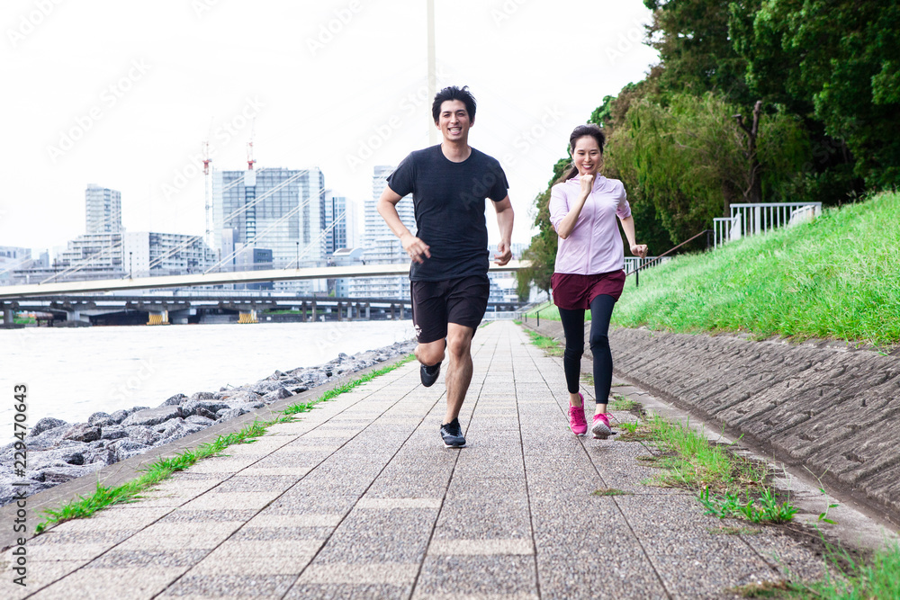 川沿いの道をランニングしている夫婦