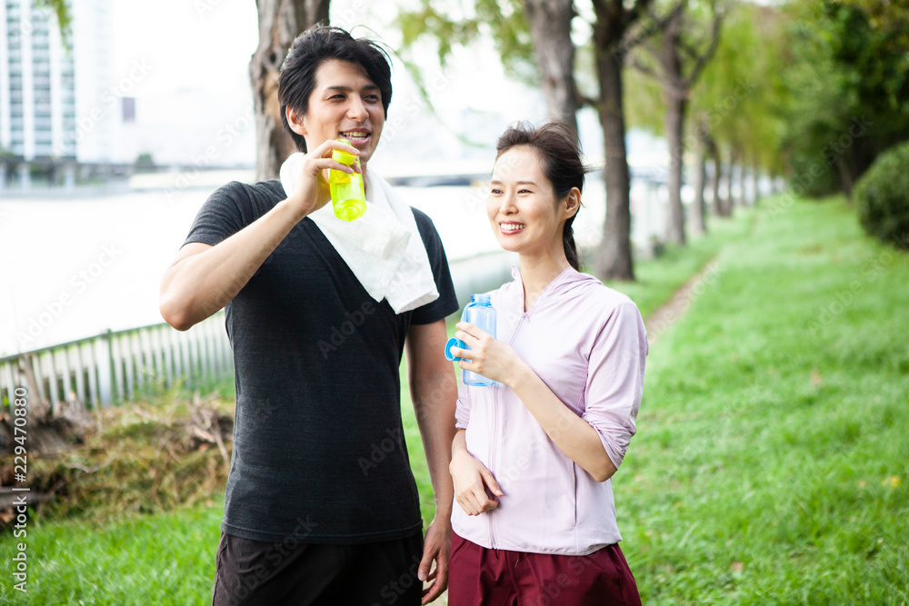 ランニングロードで、水分補給をするカップル 