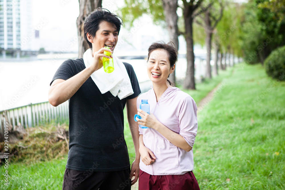 運動中に休憩し、水分補給をするカップル 