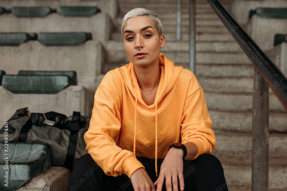 Fitness woman sitting on stairs in the stands of a stadium