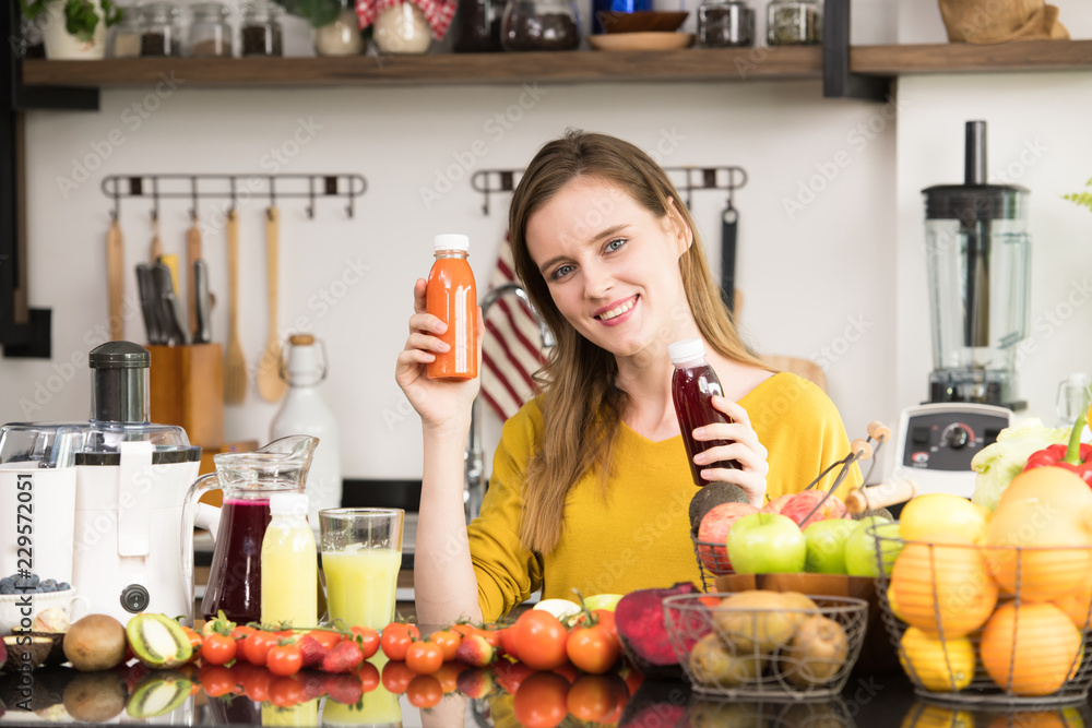 Healthy young woman in a kitchen with fruits and vegetables and juice